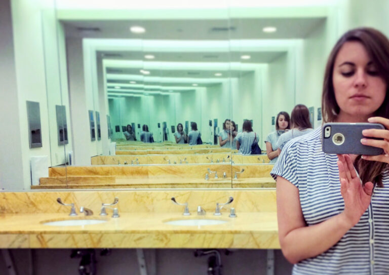 a person with their phone in an infinity mirror